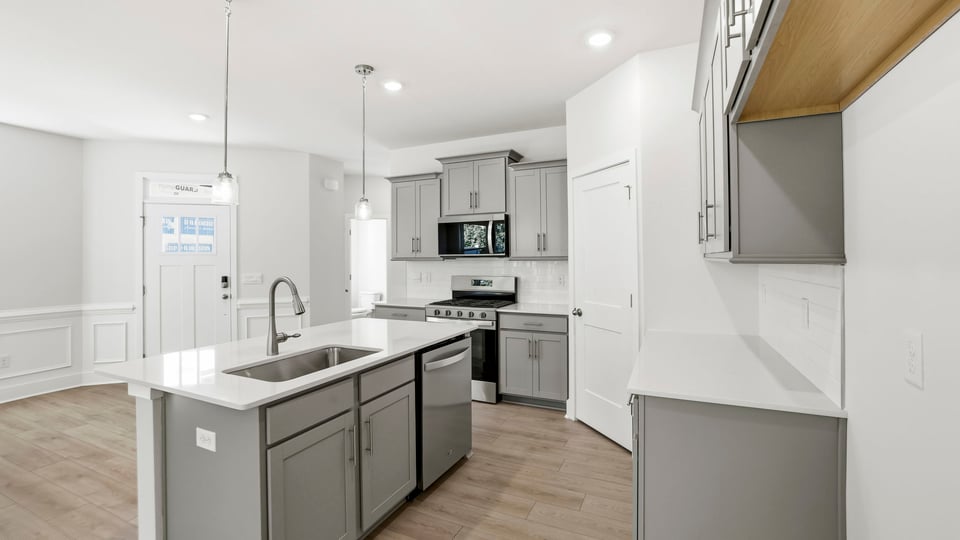 Kitchen and island with quartz countertops and stainless steel appliances.