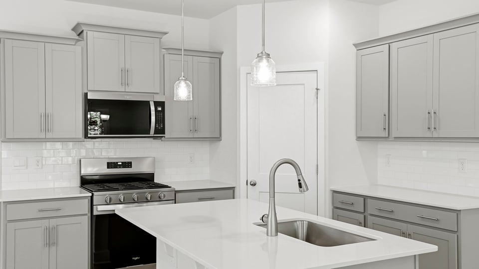 Kitchen and island with quartz countertops and stainless steel appliances.