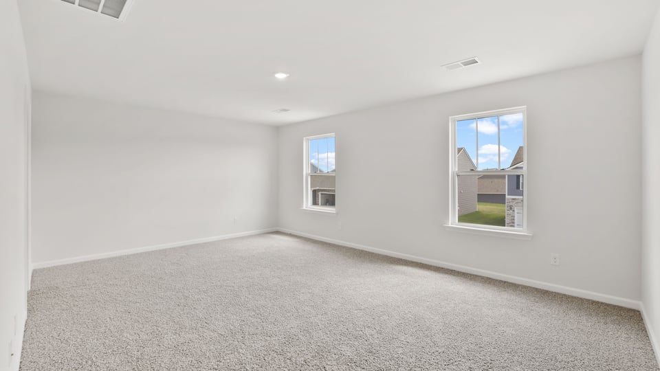 Primary bedroom with carpet and windows.