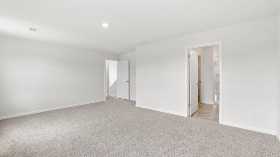 Primary bedroom with carpet and windows.