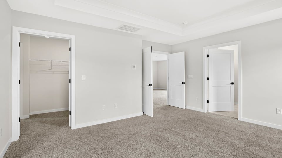 Primary bedroom with window and carpet.