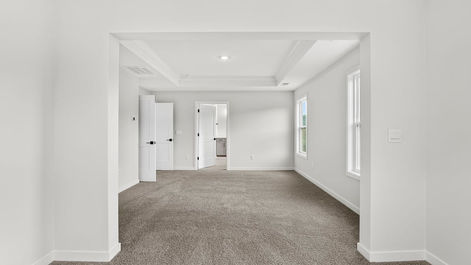 Primary bedroom with window and carpet.