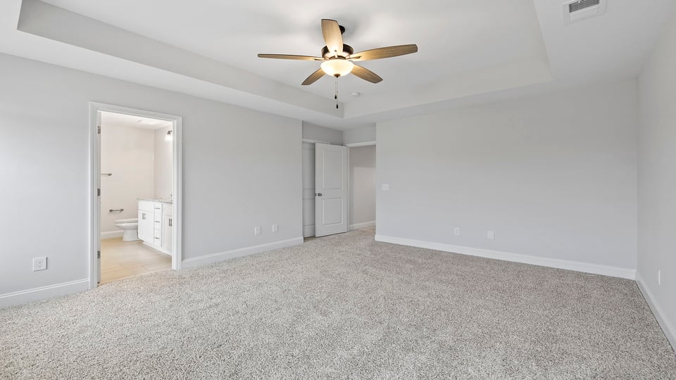 Primary bedroom with carpet and window.