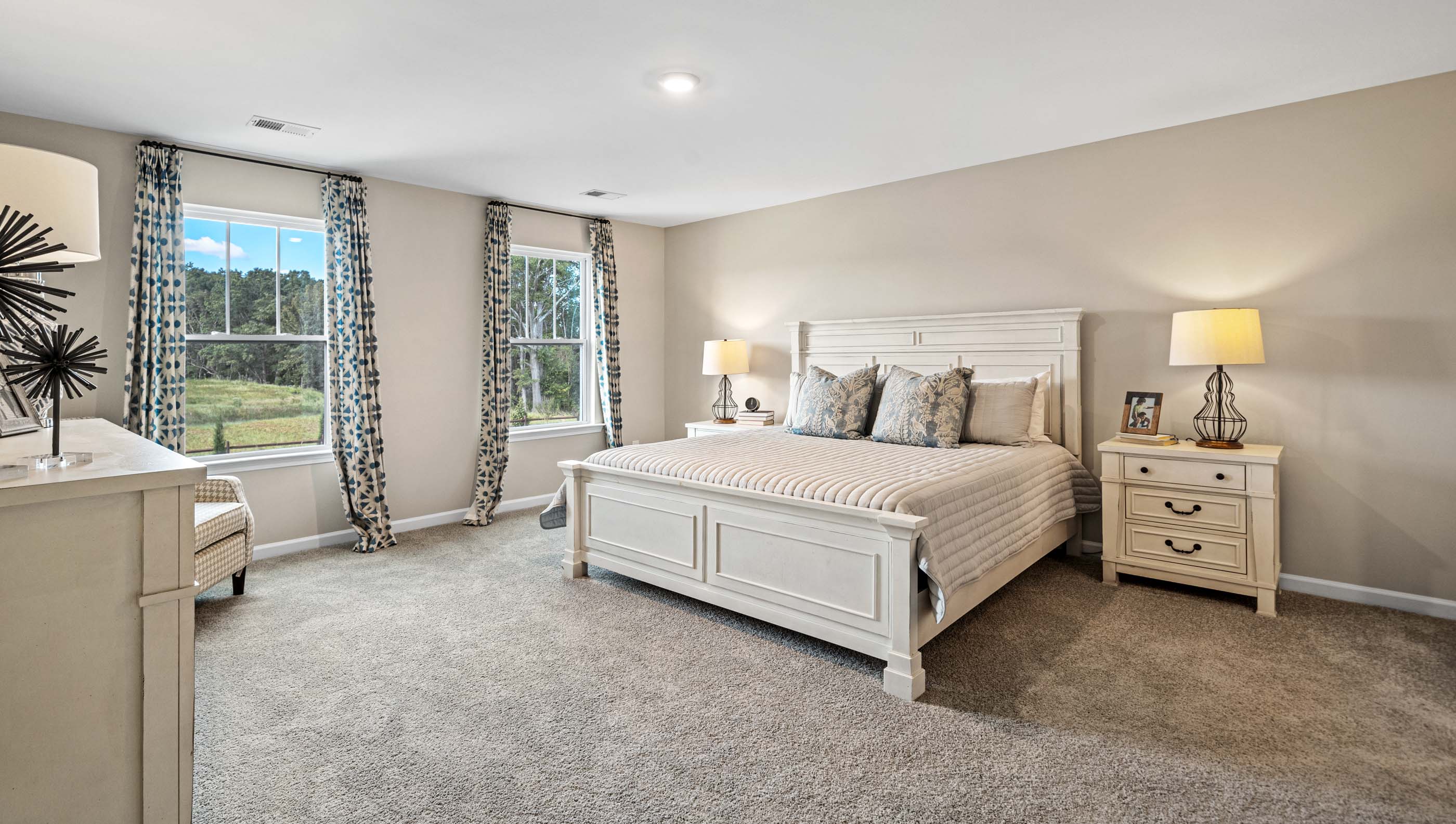 Primary bedroom with windows and carpet.