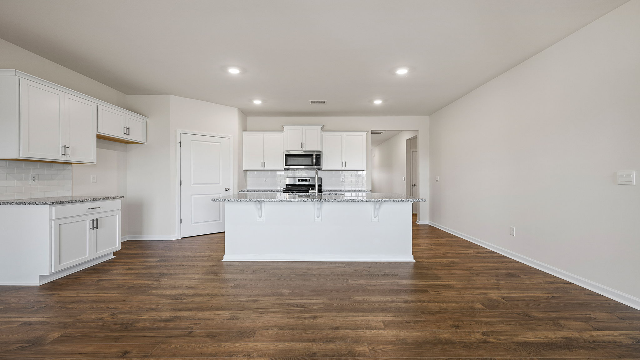 View of open kitchen and hallway to the entrance.