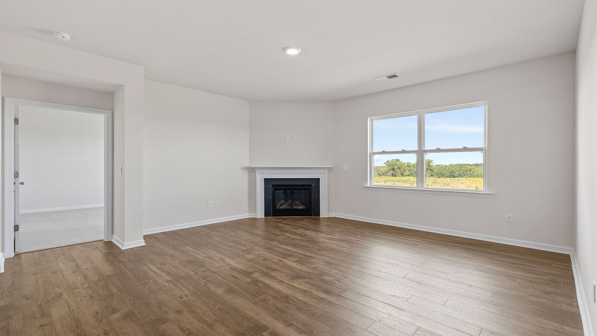 View of family room with large window and gas log fireplace.