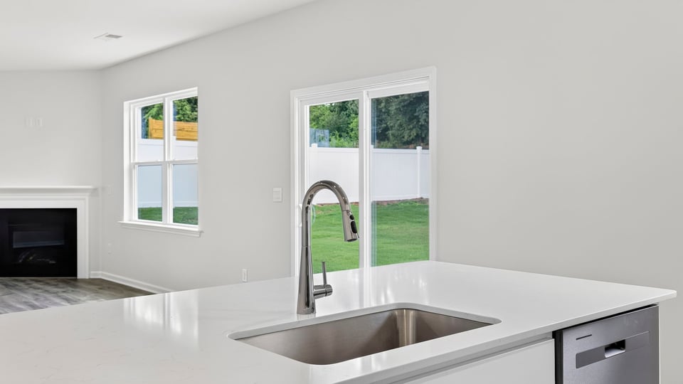Close up sink/island and living area with window and sliding glass back door