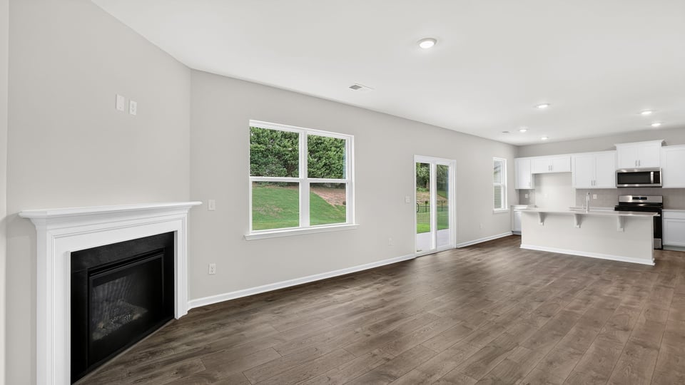 Full view of living area and kitchen with fireplace, window, and sliding glass back door