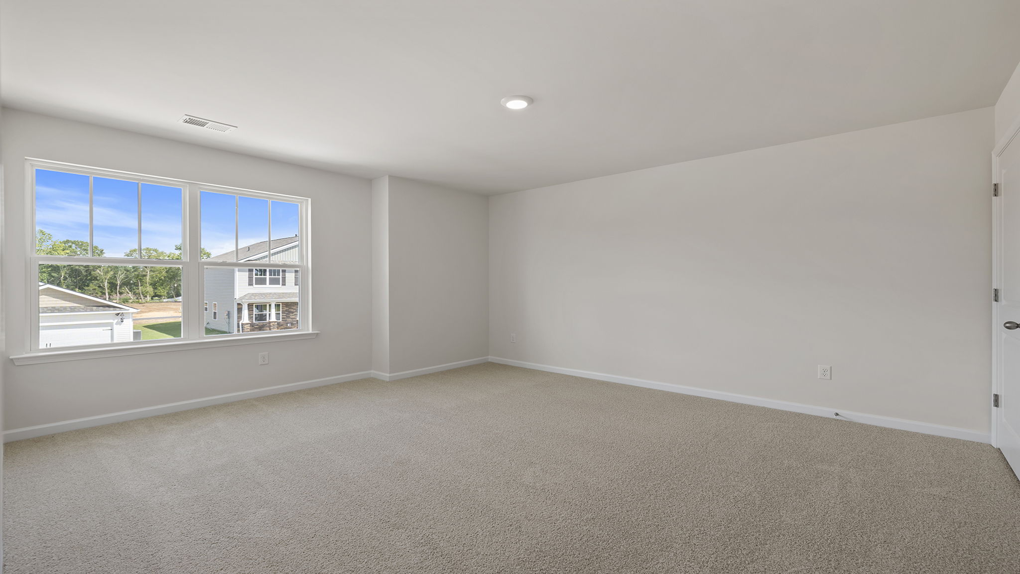 Primary bedroom with carpet and 2 large windows.