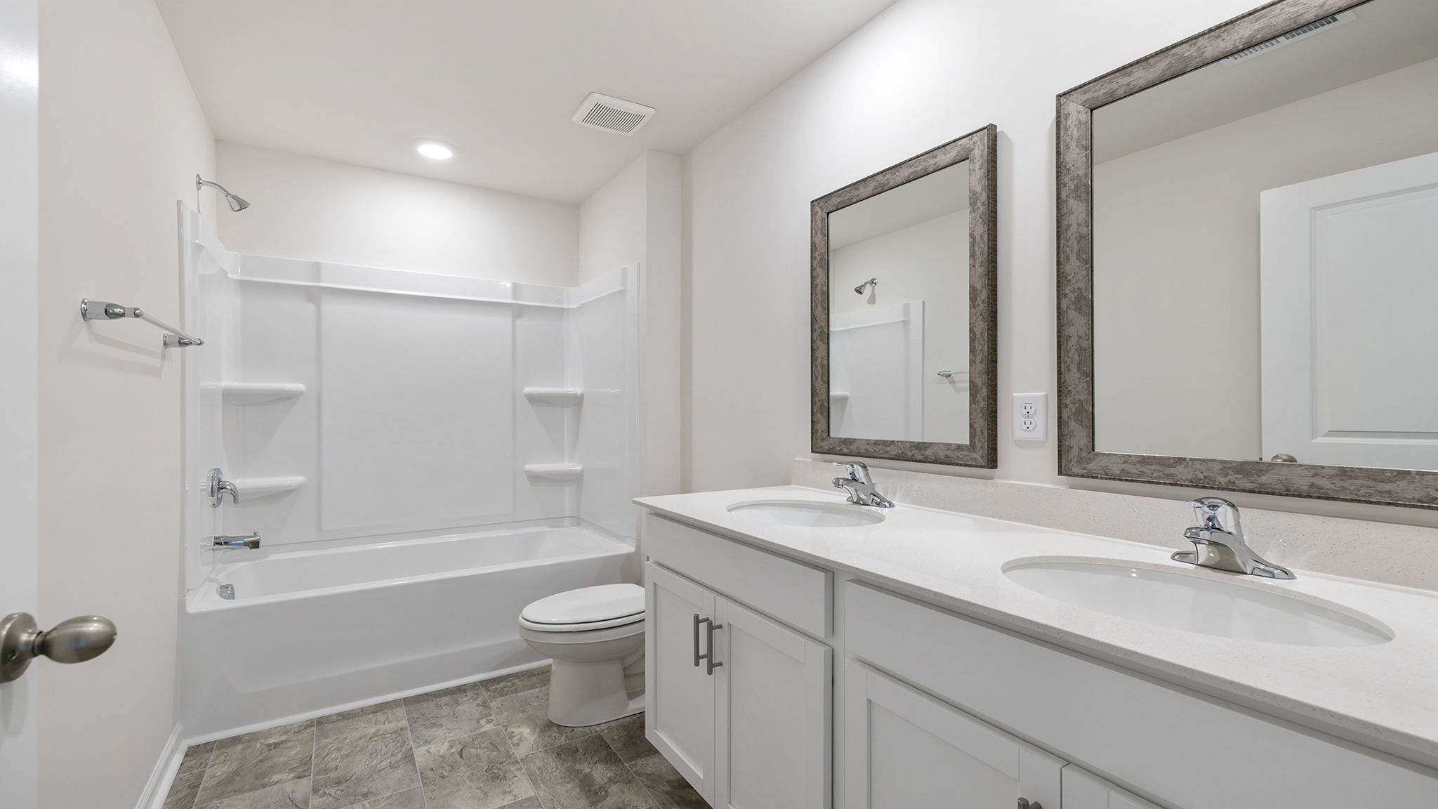 Hall bathroom with dual sink vanity and combination shower / tub.