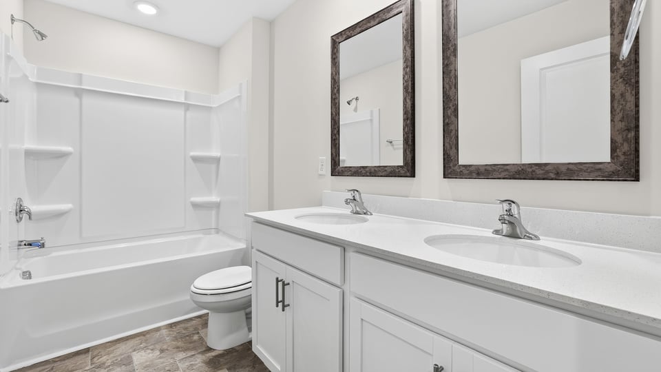 Bathroom with double vanity sink, shower, and toilet