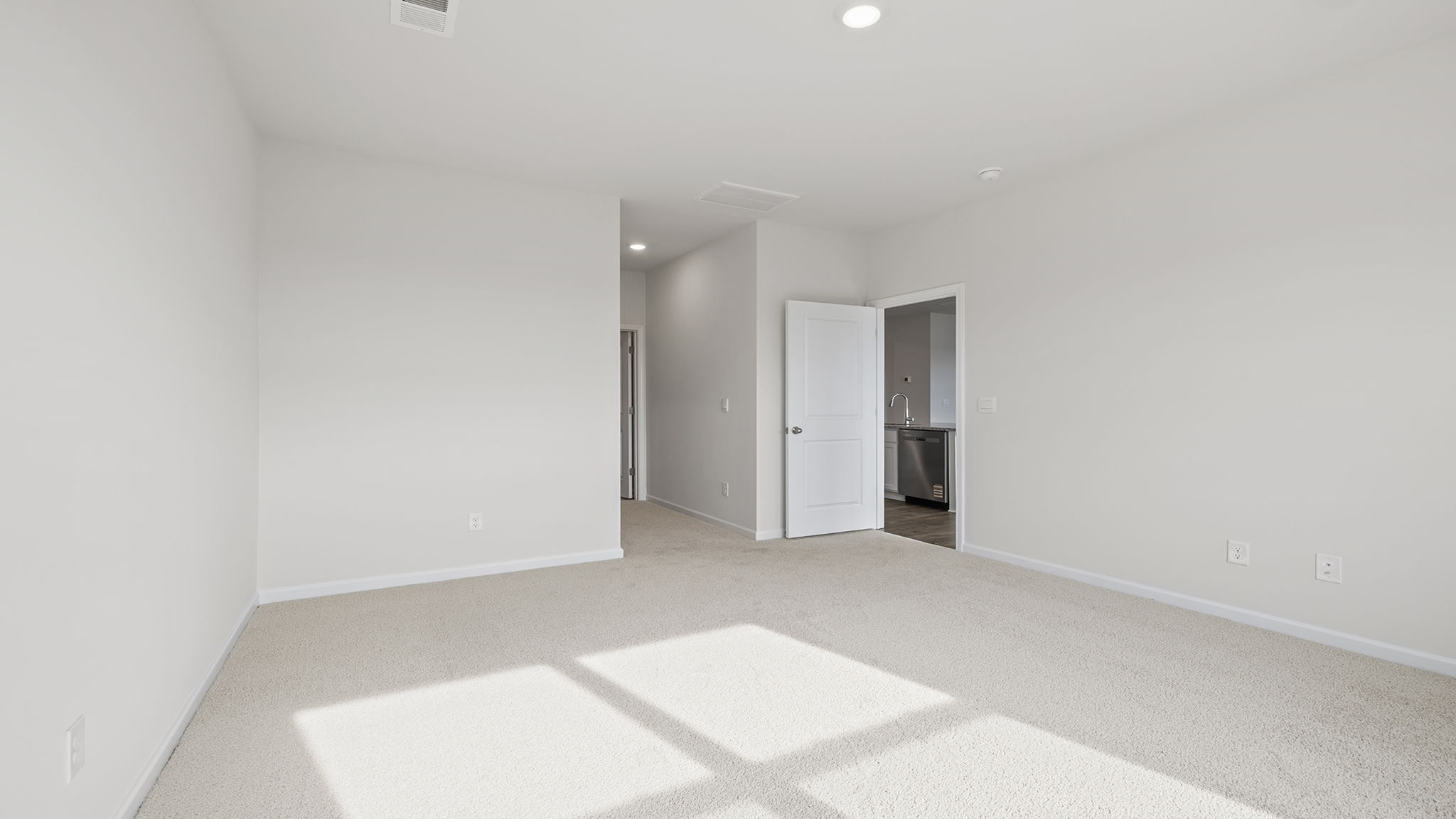 Primary bedroom with carpet and window.