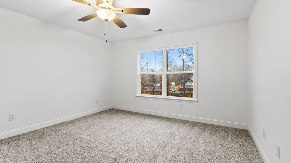 Primary bedroom with large window and carpet.