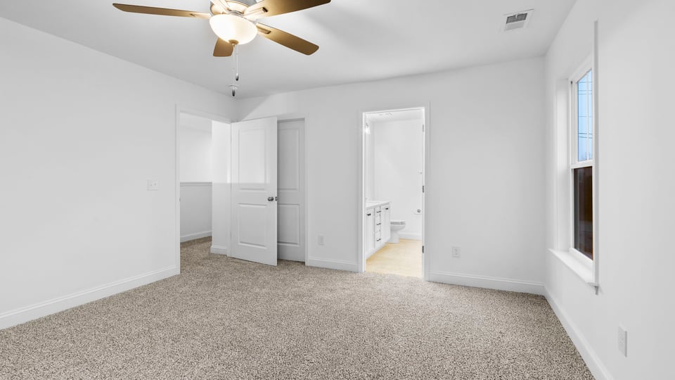 Primary bedroom with large window and carpet.
