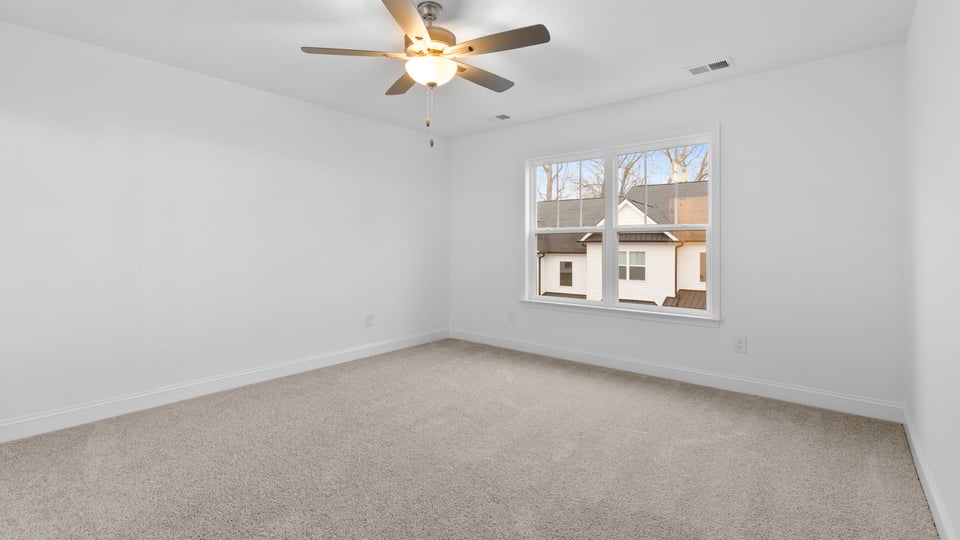 Primary bedroom with large window and carpet.