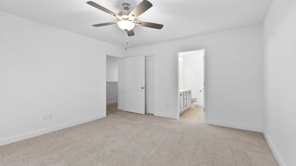 Primary bedroom with large window and carpet.
