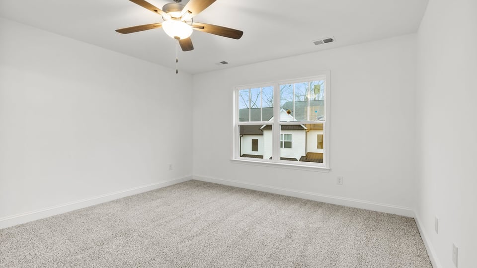 Primary bedroom with large window and carpet.