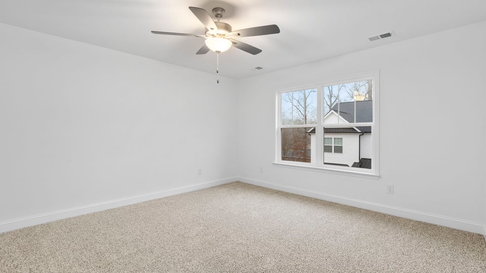 Primary bedroom with large window and carpet.