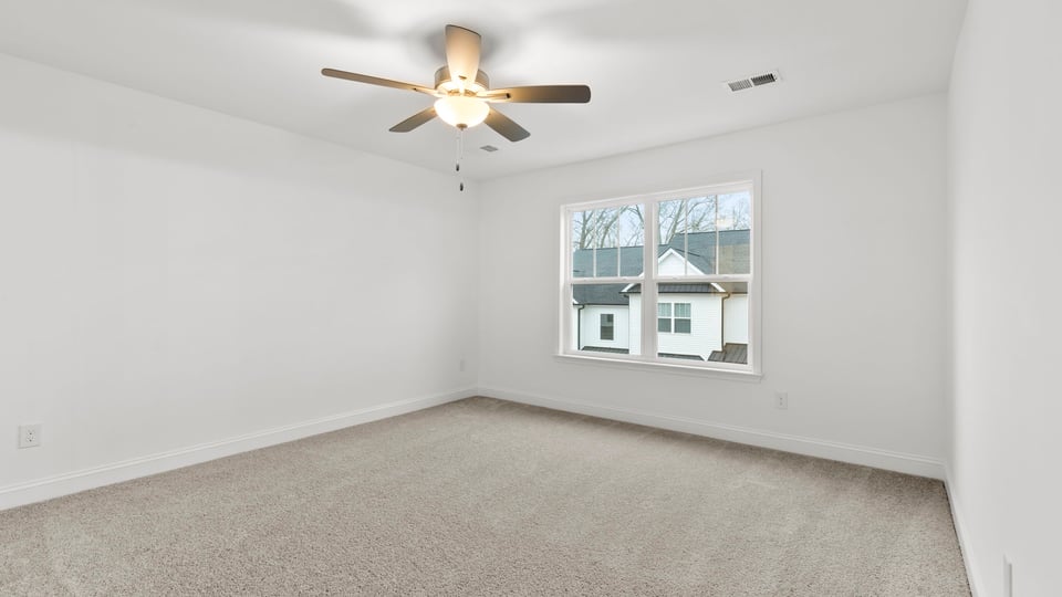 Primary bedroom with carpet and window.