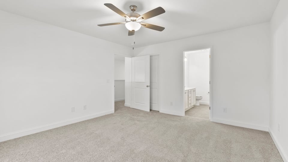 Primary bedroom with carpet and window.