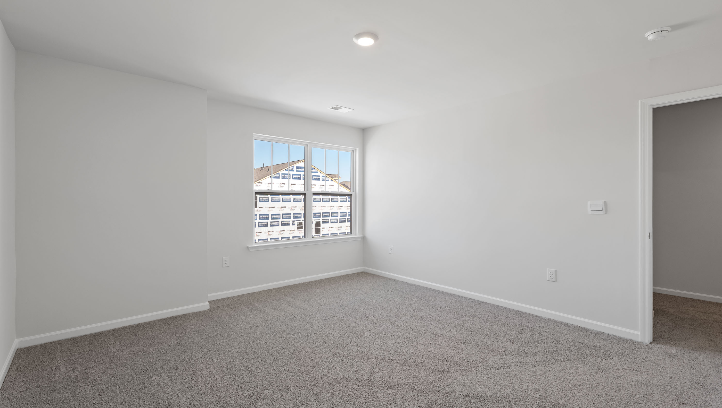 Primary bedroom with carpet and windows.