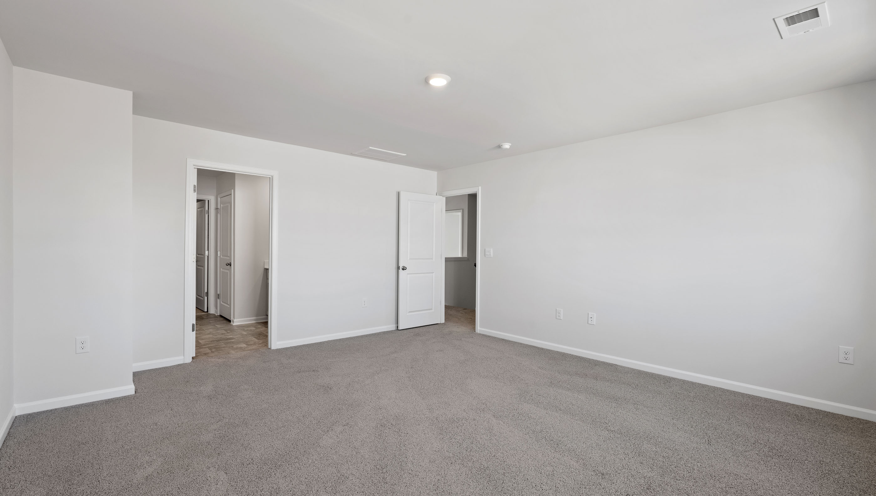 Primary bedroom with carpet and windows.