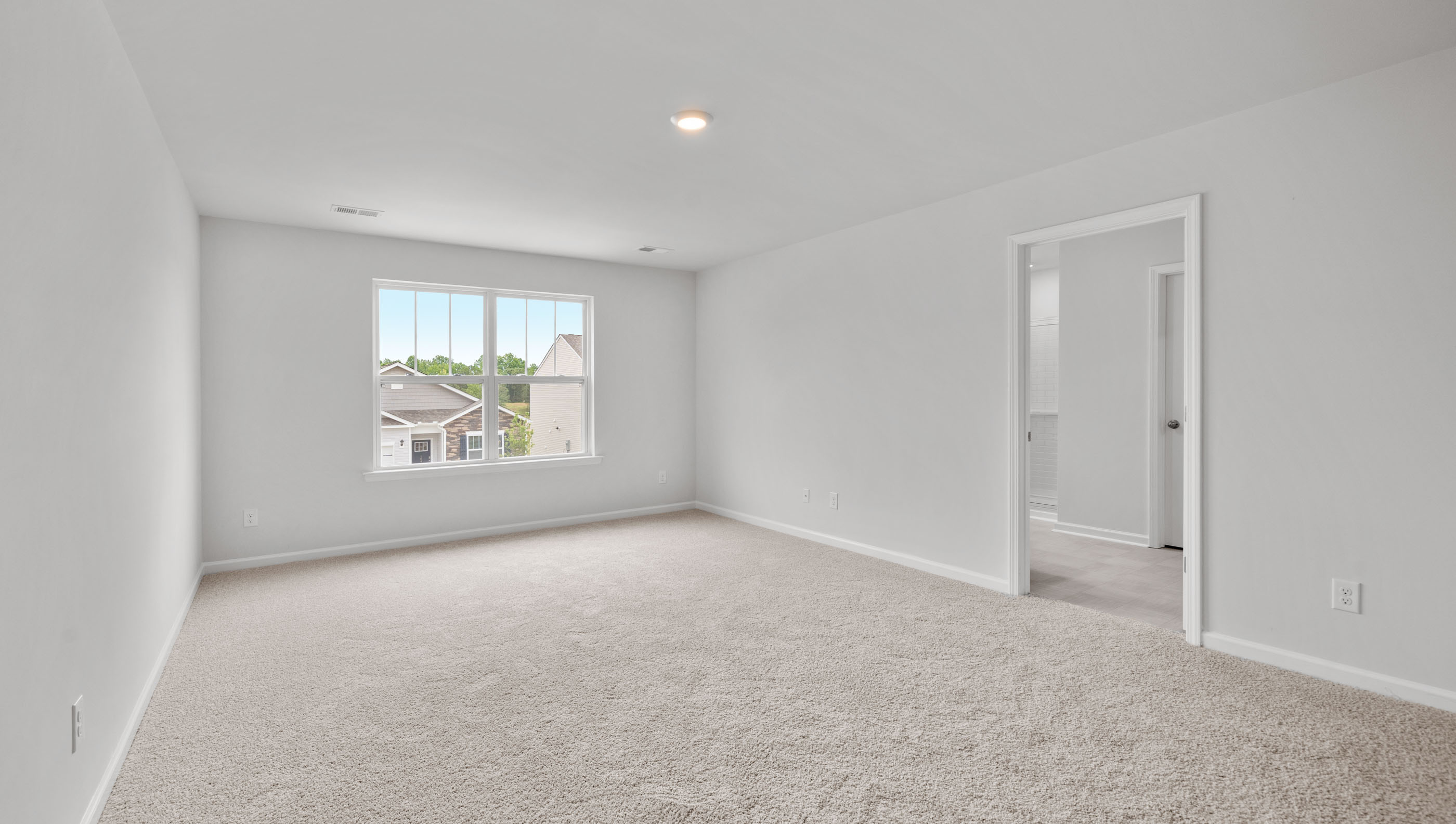 Primary bedroom with windows and carpet.