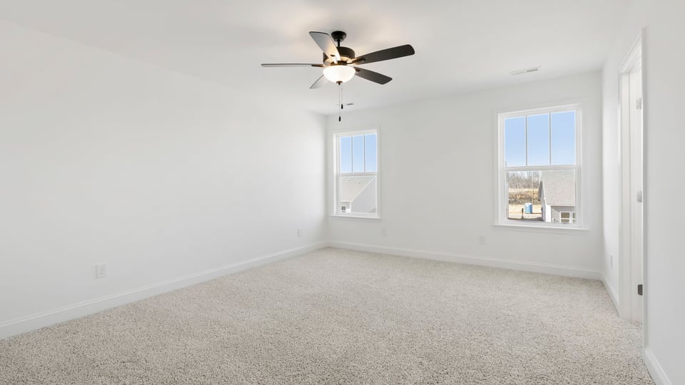 Primary bedroom with carpet and windows.