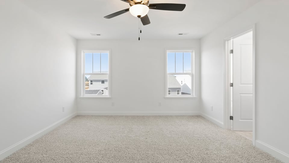 Primary bedroom with carpet and windows.