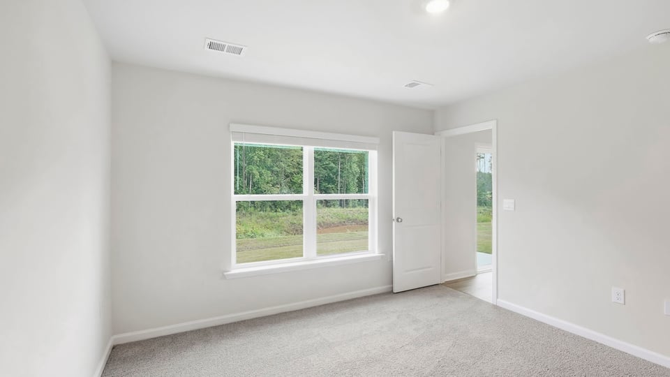 Primary bedroom with carpet and windows.