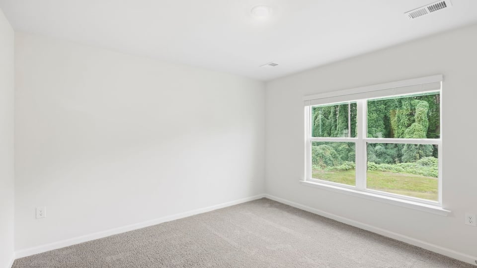 Primary bedroom with carpet and windows.