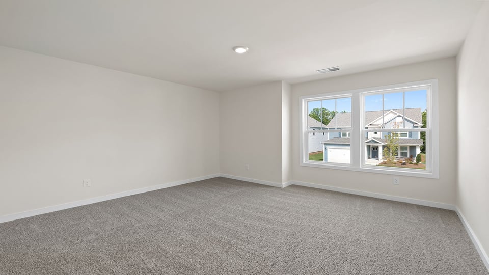 Primary bedroom with carpet and window.