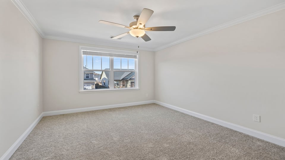 Bedroom with window, ceiling fan and carpet.