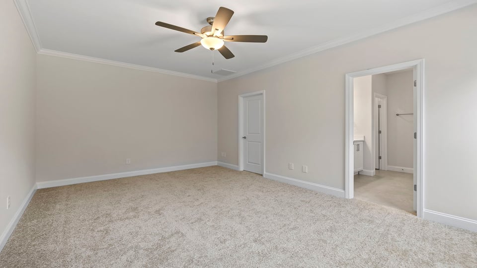 Primary bedroom with windows, ceiling fan and carpet.