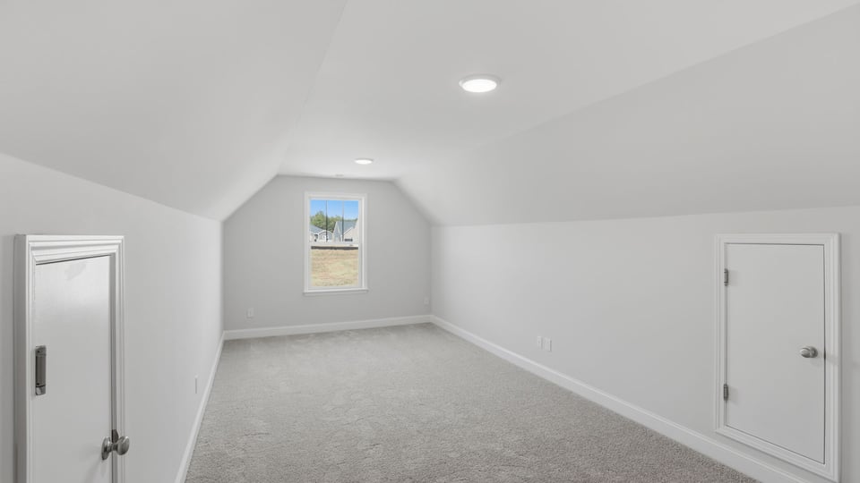 Loft space with carpet and window.