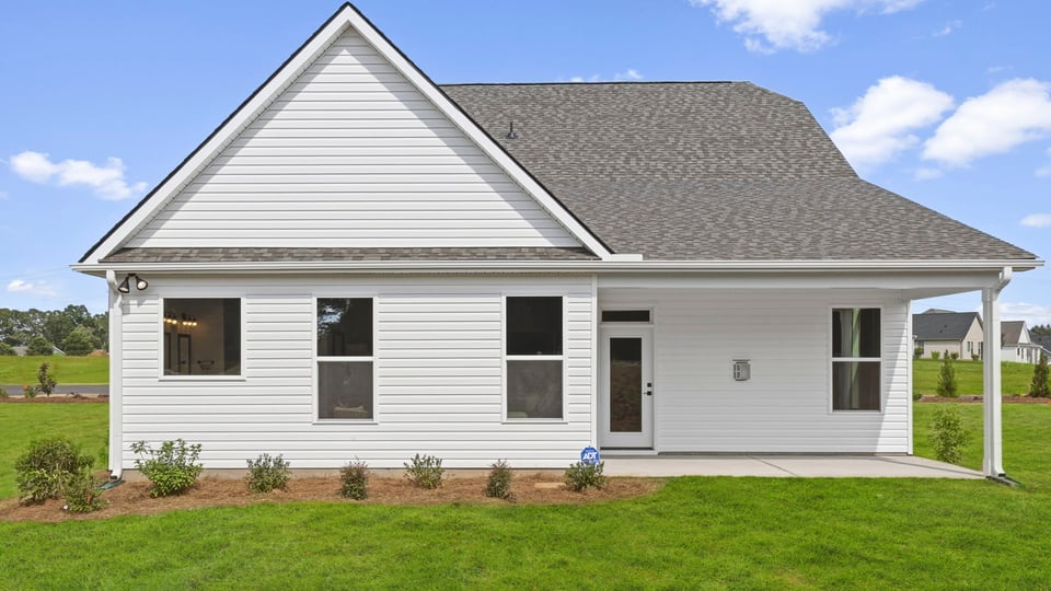 Exterior of home with covered porch and large backyard.
