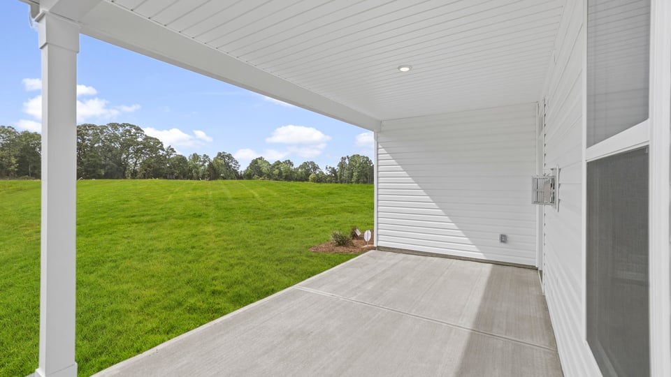 Exterior of home with covered porch and large backyard.