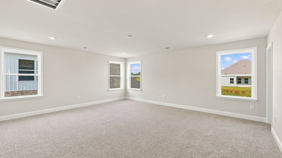 Primary bedroom wih carpet and windows.