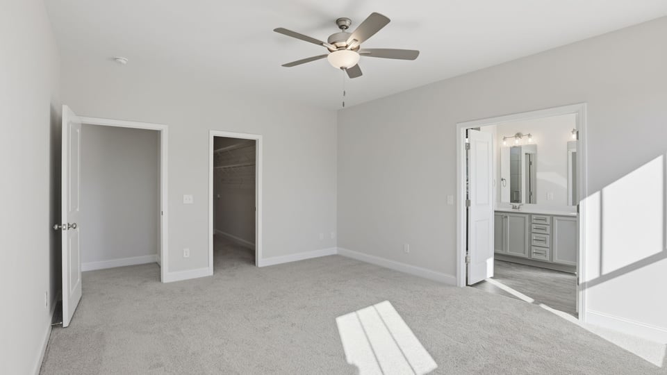 Primary bedroom on the main level with large windows and carpet.
