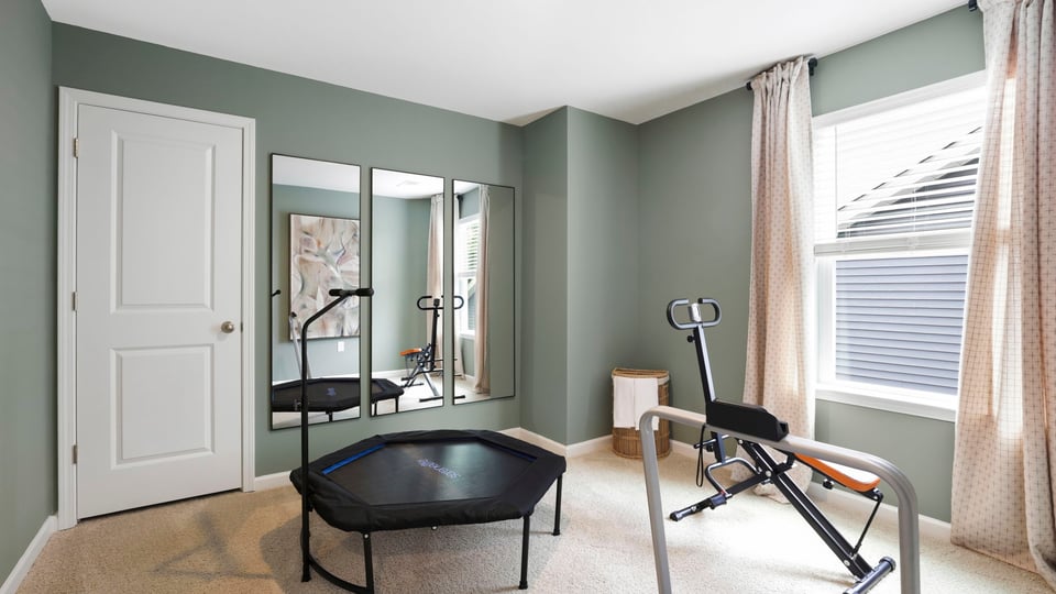 Bedroom used as gym with carpet and window.