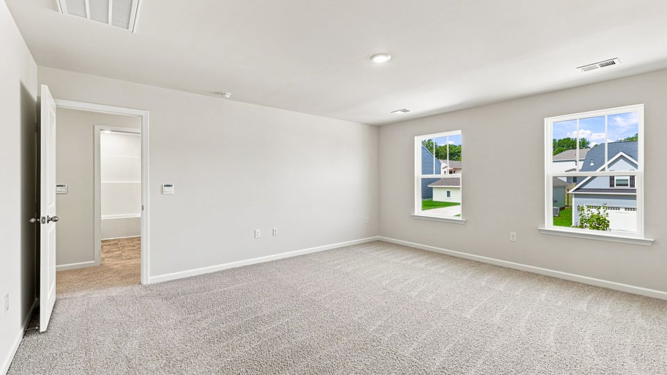 Primary bedroom with carpet and windows.