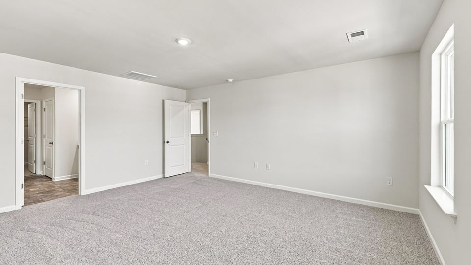 Primary bedroom with carpet and windows.