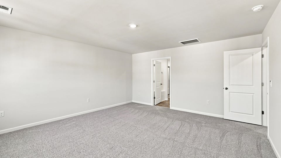 Primary bedroom with carpet and windows.