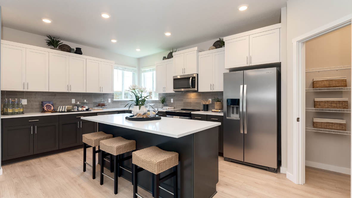 Landau Heights Kitchen with white solid surface countertops and stained shaker style cabinets and stainless steel appliances