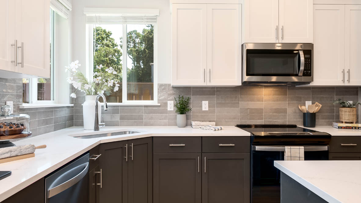 Landau Heights Kitchen with white solid surface countertops and stained shaker style cabinets and stainless steel appliances