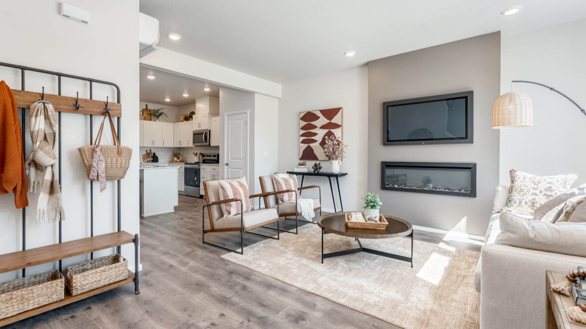 Terrace at Pleasant Valley Great room with a white couch and pillows, coat rack electric fireplace, chair, white rug, wood coffee table, laminate flooring, and a window