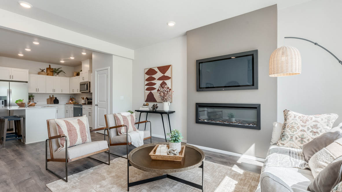 Terrace at Pleasant Valley Great room with a white couch and pillows, coat rack electric fireplace, chair, white rug, wood coffee table, laminate flooring, and a window