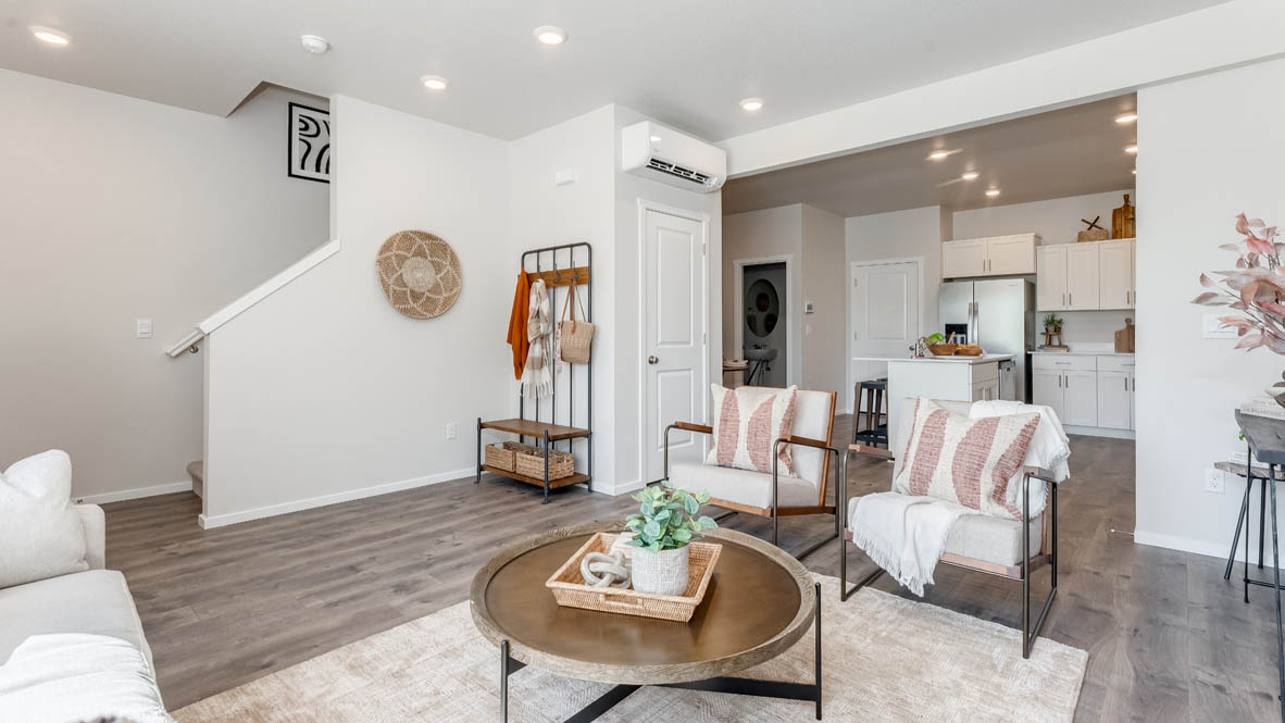 Terrace at Pleasant Valley Great room with a coffee table, a brown chair, white area rug, laminate flooring, and the kitchen in the background