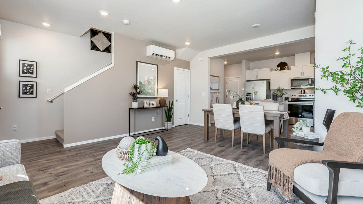 Terrace at Pleasant Valley Great room with a coffee table, a brown chair, white area rug, laminate flooring, and the kitchen in the background