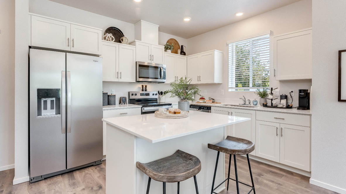 Kitchen with shaker cabinets, quartz counters, stainless steel appliances, pantry, and an island with a breakfast bar